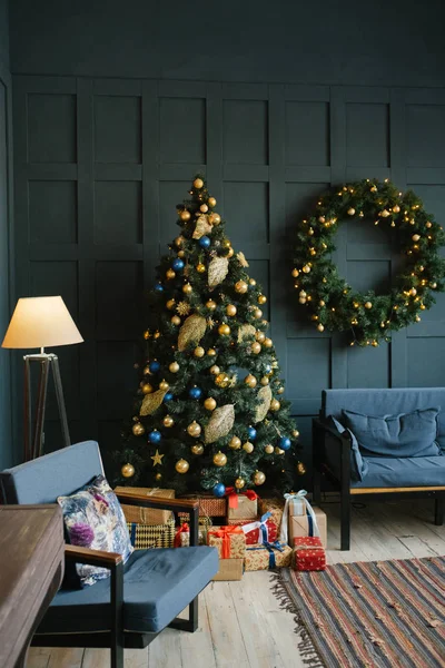 Christmas wreath on the wall, spruce and sofa in the living room with blue walls