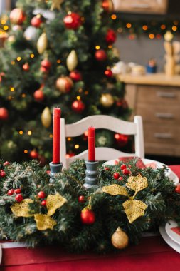 Oturma odasındaki masada kırmızı mumlar olan Noel çelengi mi yoksa evdeki yemek odası mı?