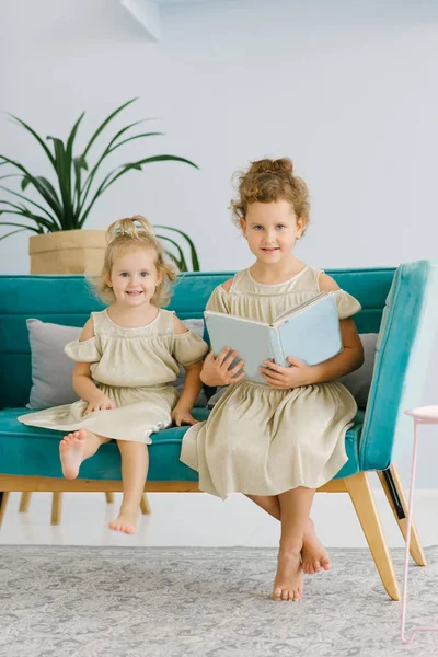 Two Baby Girls Sitting Blue Sofa Smiling One Them Holding — Stock Photo, Image