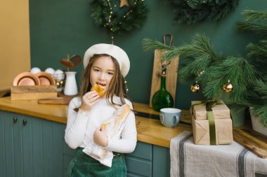 Beyaz bereli şık bir kız, küçük bir Fransız kadın gibi, bir parça baget kopardı ve onu ısırdı ve Noel mutfağının arka planında yemek yedi. Lezzetli Noel menüsü