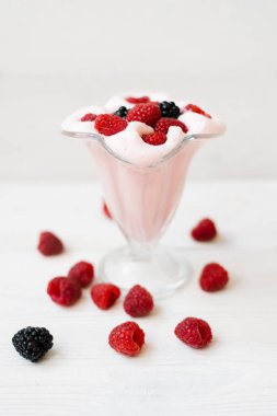 Beyaz ahşap arka planda güzel bir cam üzerinde yabani böğürtlenli milkshake. Ferahlatıcı, serinletici yaz içkileri konsepti. Seçici odak