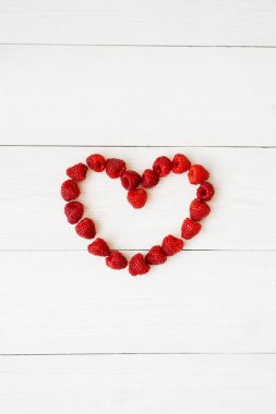 Taze organik böğürtlenlerin kalbi beyaz ahşap bir zeminde