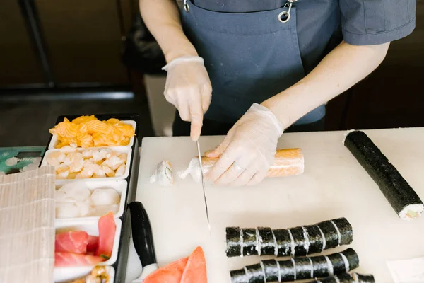 Chef cuts sushi with a knife, cooking Japanese sushi in a restaurant man, close-up