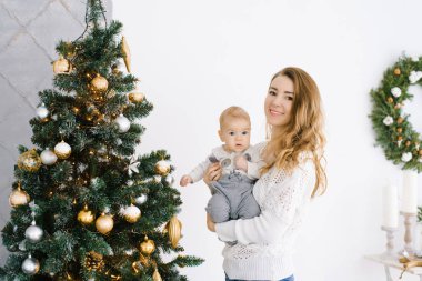 Genç bir anne, küçük oğlunu kollarının arasına alıp oturma odasında bir Noel ağacının arkasına yaslar. Yeni yılı kutlayıp Noel 'i kutlayacaklar.