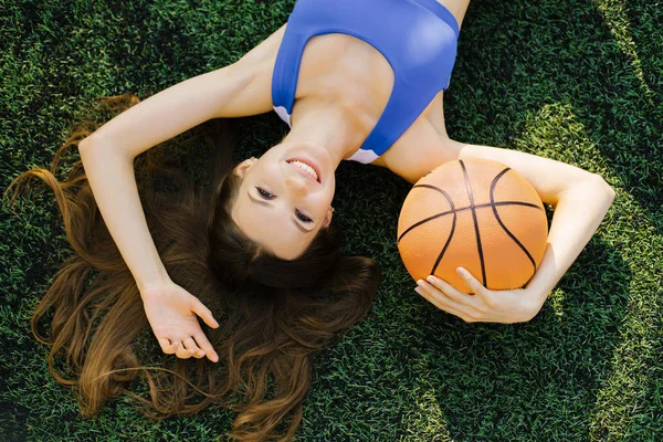 草の上の芝生の上に横たわってバスケットボール選手ですバスケットボールの周りに腕を置きます — ストック写真