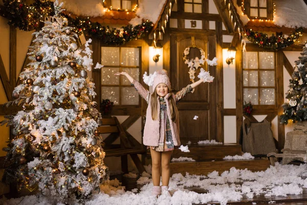 Девушка Держит Руки Вверх Посыпает Снег Фоне Рождественского Дома Рождественской — стоковое фото