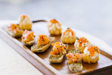 Ahşap tabakta somon ya da somonlu abur cuburlar seçici bir odak noktasıyla yaklaşır.