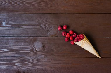 Kahverengi tahta üzerinde waffle külahında taze organik ahududu.