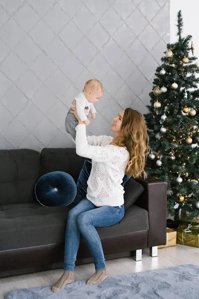 Uma Jovem Mãe Camisola Branca Jeans Senta Sofá Perto Árvore — Fotografia de Stock