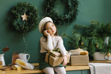 Kucağında Noel 'i tutan güzel bir kız ya da zümrüt mutfağının içinde yeni yıl hediyesi ve hayalleri.