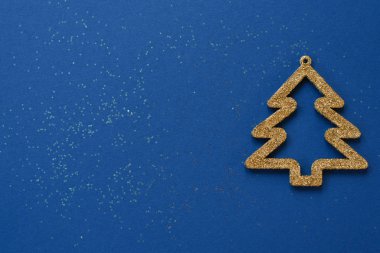 Pullu zengin mavi arkaplan rengi ve fotokopi alanı için altın Noel ağacı süslemesi. Noel ve yeni yıl tebrik kartı