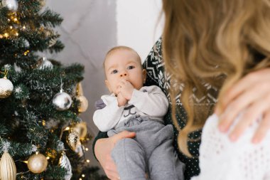 Küçük bir çocuk Pope 'u yakın planda tutuyor. Noel için dekore edilmiş bir oturma odasında bir çocuk ellerini ağzında tutuyor. Mutlu mutlu bir aile