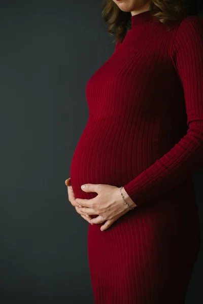 Eine Schwangere Frau Einem Weinroten Strickkleid Hält Ihre Hände Auf — Stockfoto