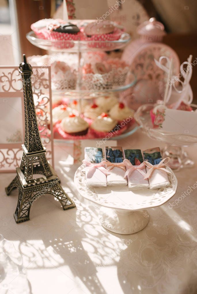 Wedding sweet table in pink. Chocolates and Eiffel tower statuette in candy bar decor