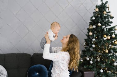 Mutlu bir anne oğlunu kollarına alır ve Noel ve yeni yıl süsleri içinde oturma odasındaki kanepede onunla oturur. Anne, oğlunu yukarı kaldırdı. Mutlu annelik