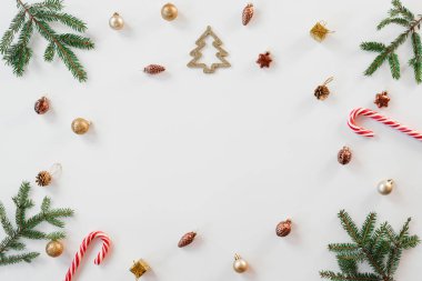 Yaratıcı Noel ağacı oyuncakları, baston şeklinde nane şekeri, beyaz arka planda köknar dalları. Noel ve yeni yıl tatili. Düz yatış, üst görünüm