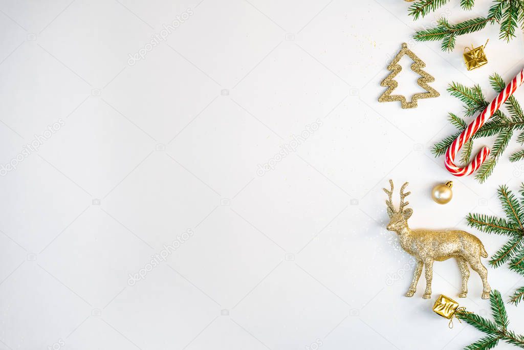 New year and Christmas composition. Border frame of gold Christmas toys, fir branches, deer on a white paper background. The view from the top, flat position, where you want to copy. Holiday card