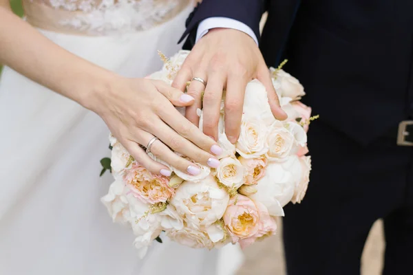 結婚式の繊細な花束に結婚指輪と新郎新婦の手 — ストック写真