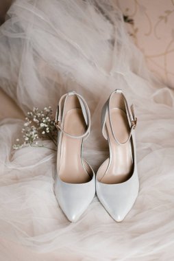 Gelin için açık gri ayakkabılar ve beyaz bir tül üzerinde bir çigila filizi. Kadınlar için aksesuarlar