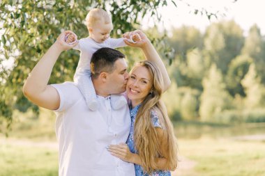 Küçük çocuğu olan mutlu bir aile. Babam annemi yanağından öpüyor, annem mutlu ve gülümsüyor..