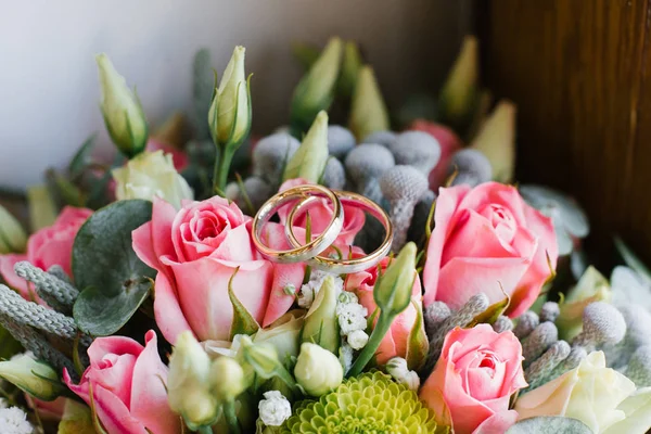 Золоті обручки на яскравих весільних квітах крупним планом — стокове фото