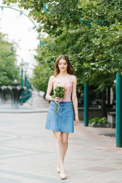 Krásná dívka v jemné růžové horní a džínové sukně venku. — Stock fotografie