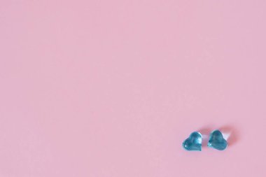 Güzel bir pembe pastel arka planda cam kalpler. İki mavi çalı