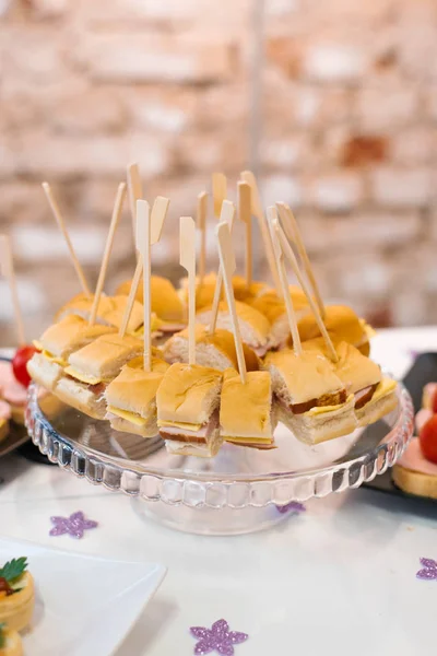 Snacks canapés en un plato de vidrio redondo en una mesa de banquete festivo — Foto de Stock