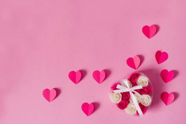 Ahududu pembesi kağıt kalpler ve pembe bir kupa üzerinde gül tomurcukları