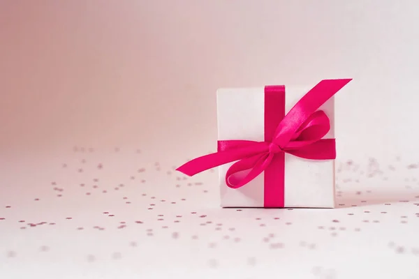 Witte geschenkdoos met roze satijnen lint. Minimalistische wenskaart — Stockfoto