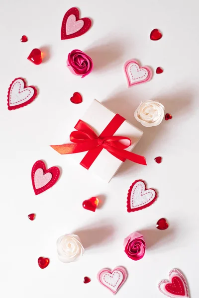 A small festive gift white box with a red bow and different type — Stock Photo, Image
