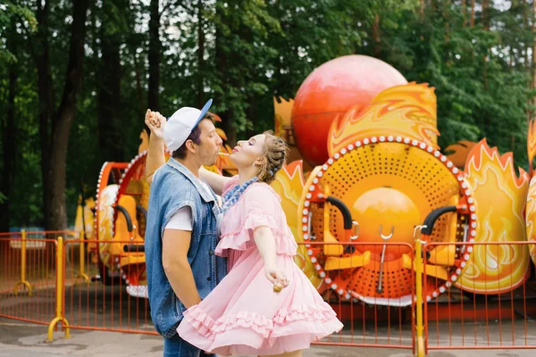 Brilhante casal alegre no amor descansando em um parque de diversões e — Fotografia de Stock