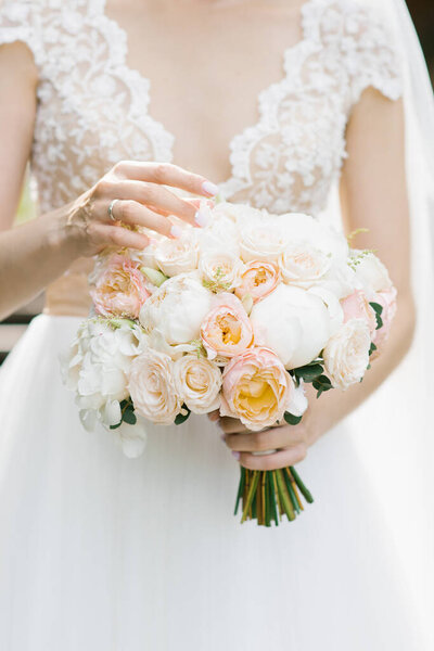 bride touches her fingers to the flowers in the wedding bouquet,