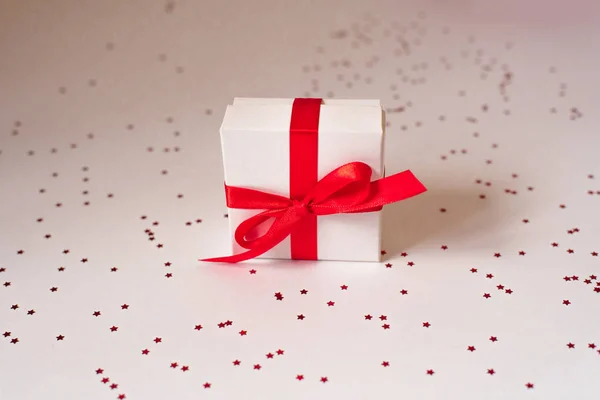 Kırmızı saten bir kurdeleyle bağlanmış beyaz hediye kutusu. — Stok fotoğraf