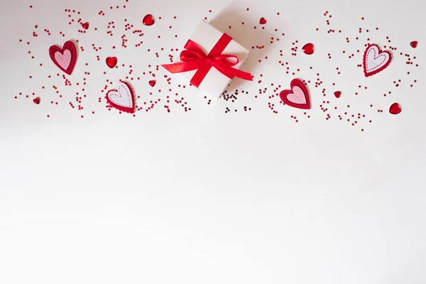 Border of gift with red bow, glass and felt hearts on white back — Stock Photo, Image