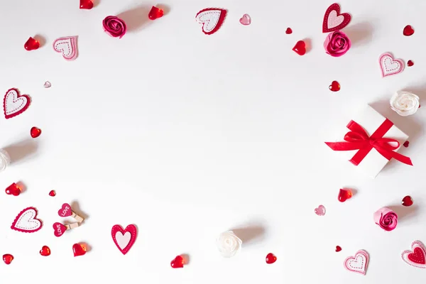 A gift frame with a red bow, beads, glass and felt hearts on a w