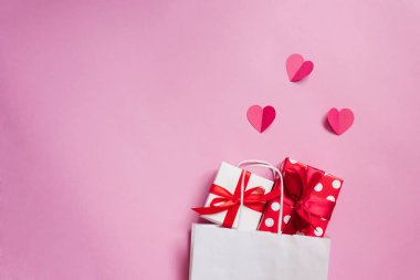  Sevgililer Günü. İçinde hediyeler ve kağıt kalpler olan beyaz bir kese kağıdı.