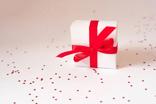 White gift box with red satin ribbon and bow on a white backgrou — ストック写真