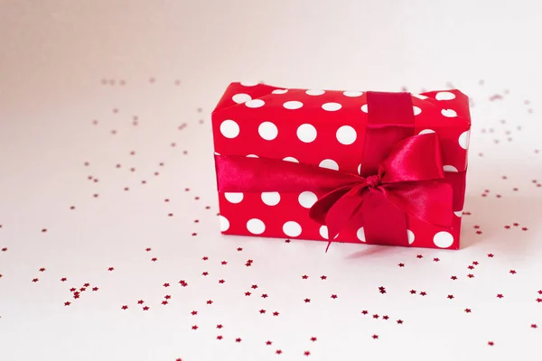 A gift wrapped in red paper with white circles and a red satin b — Stock Photo, Image