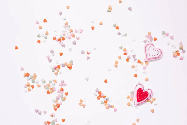 Confetti multi-colored hearts on a white background and two felt — ストック写真