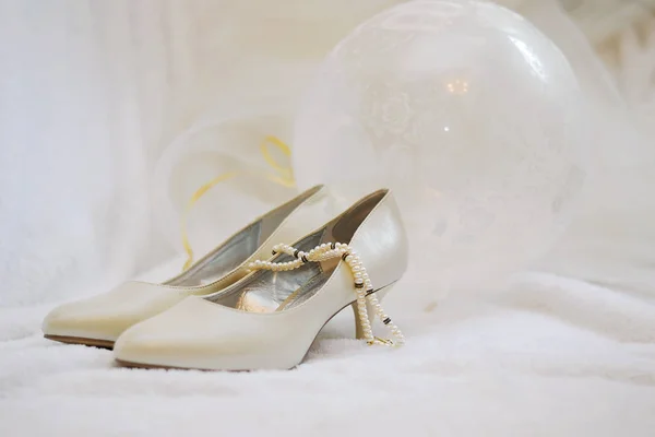 Dámské béžové nebo slonovinové boty, vedle korálků a balónu — Stock fotografie