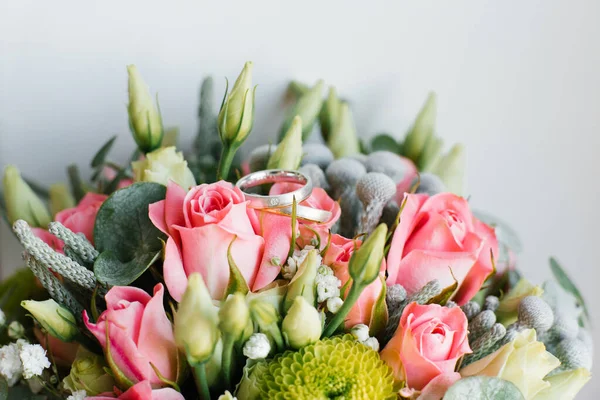 Trauringe der Braut und des Bräutigams liegen auf den Blumen des — Stockfoto