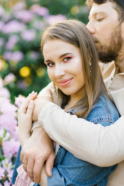 En romantisk par i kärlek omfamna på våren i en blommande rh — Stockfoto