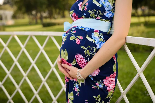 Vientre de una mujer embarazada que sostiene su estómago con su mano —  Fotos de Stock