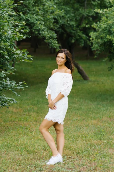 Beautiful brunette in a white dress in a clearing near the fores — 스톡 사진