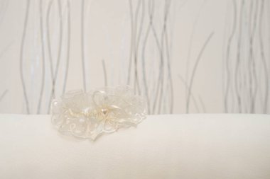 Beyaz dantelli jartiyer, parlak bir arka planda inci kalpli gelin için.