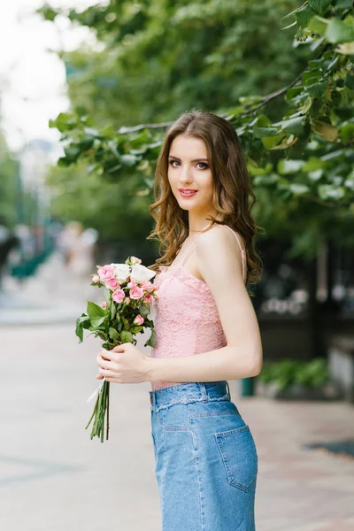 Una hermosa joven romántica en una falda corta de mezclilla sostiene una — Foto de Stock