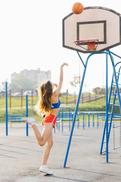 Una hermosa chica atlética esbelta juega baloncesto en el Playgr — Foto de Stock