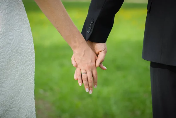 A noiva e o noivo seguram as mãos um do outro — Fotografia de Stock