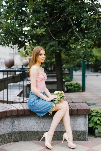Ένα όμορφο ρομαντικό κορίτσι σε ένα ροζ τοπ και τζιν φούστα εκμετάλλευση — Φωτογραφία Αρχείου